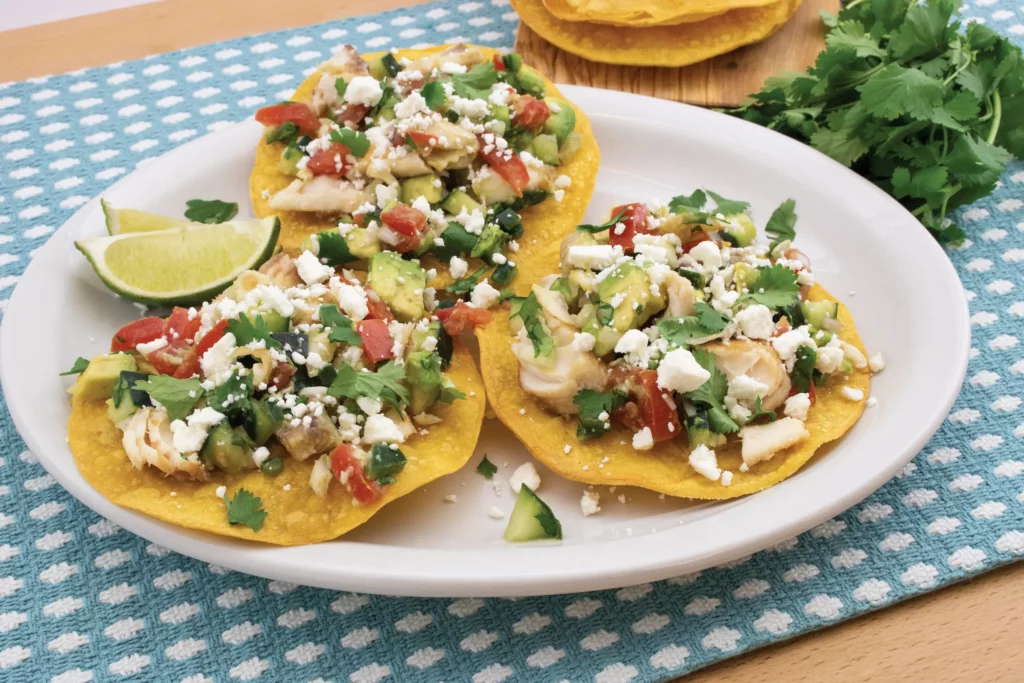 Tilapia tostadas plated topped with avocado and tomato