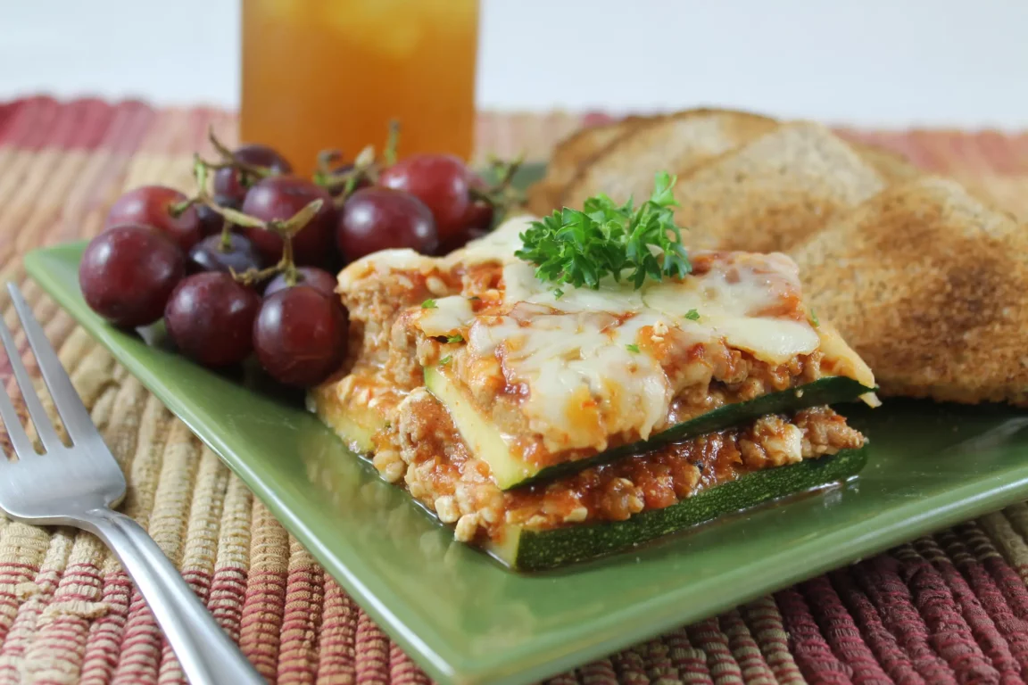 Lasagna paired with purple grapes and toasted bread.