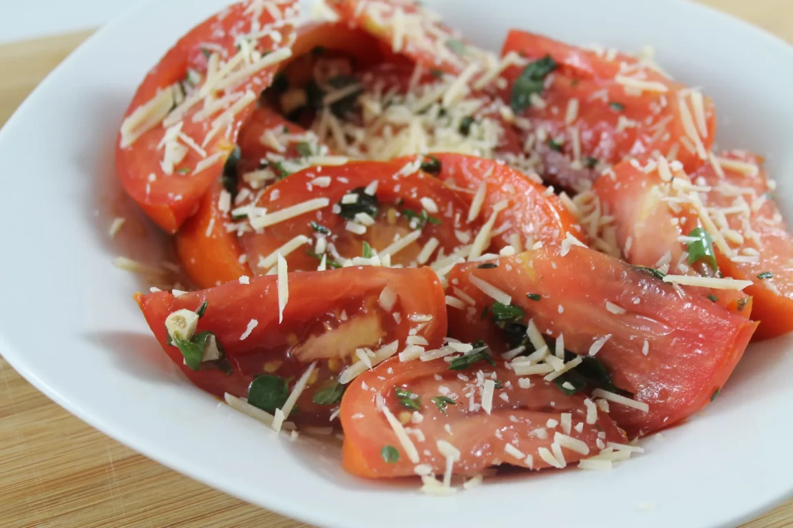 Tomato salad plated with cheese and herbs.