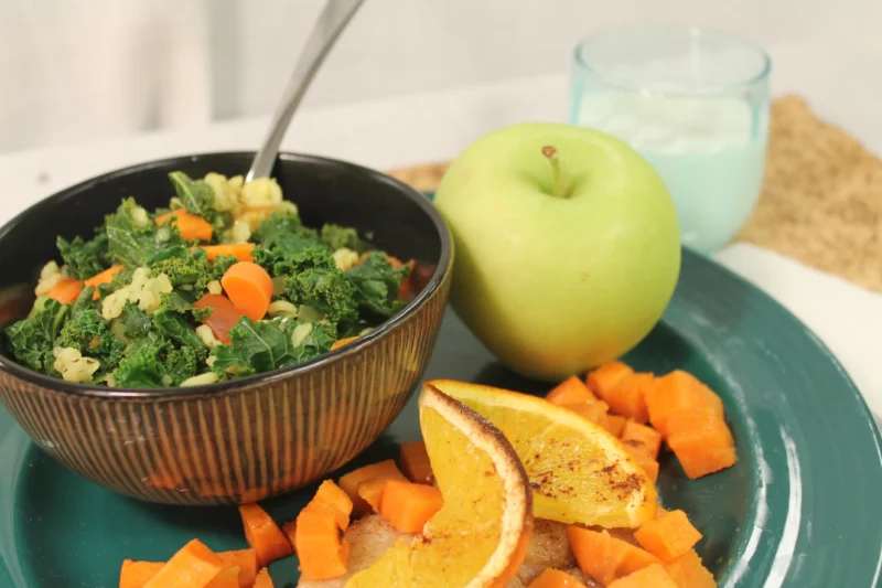 bowl of kale barley soup with side of chicken and green apple