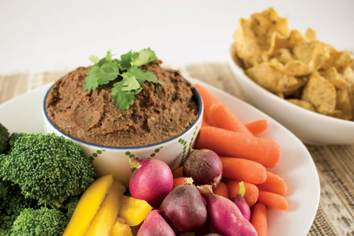 Black bean dip served with chips and cut vegetables.