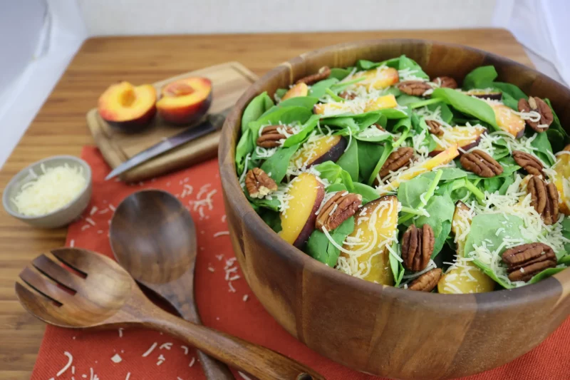 wooden bowl of peachy pecan spinach salad