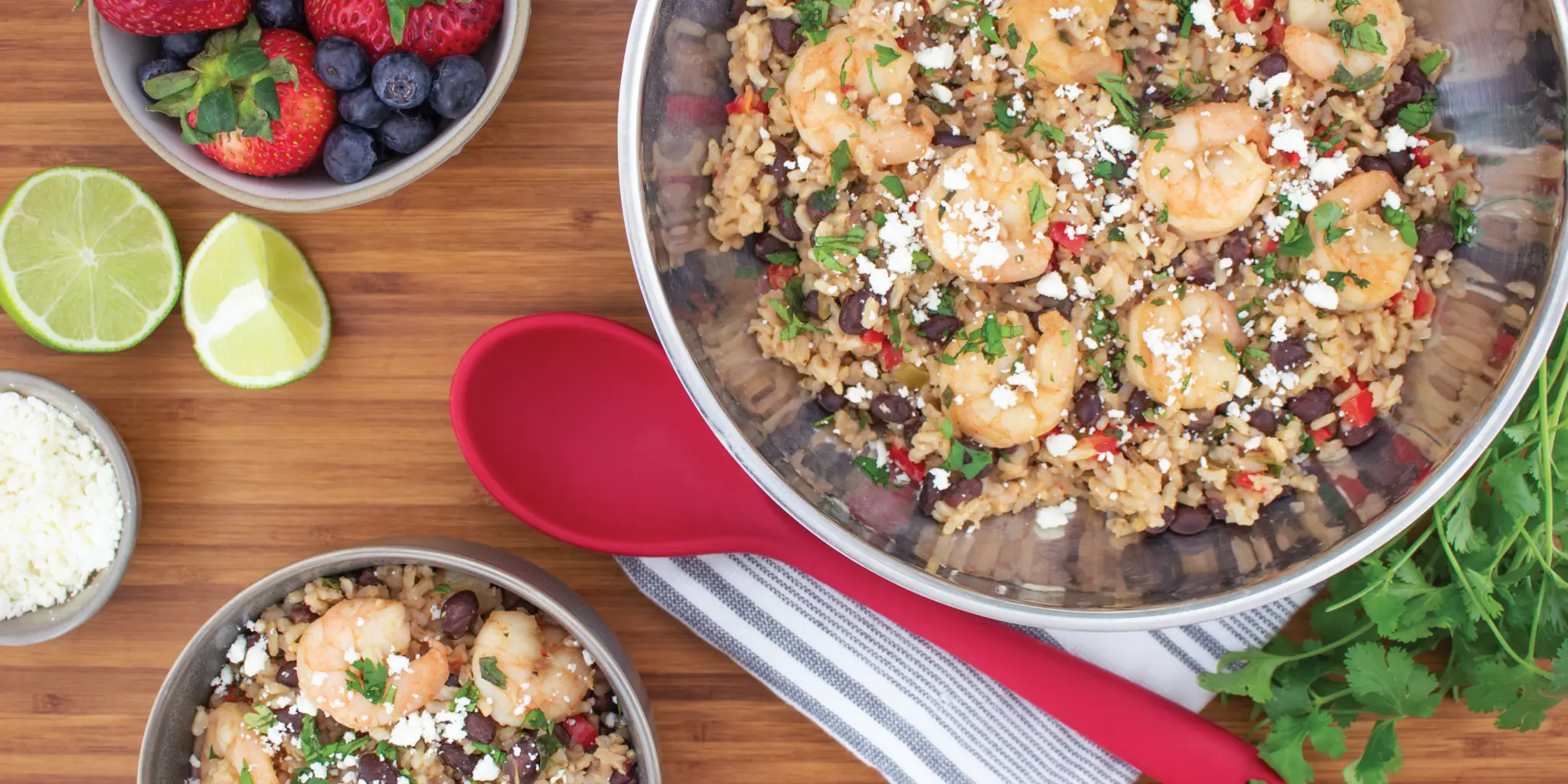 brown rice and shrimp with black beans in skillet with a plated bowl on the side