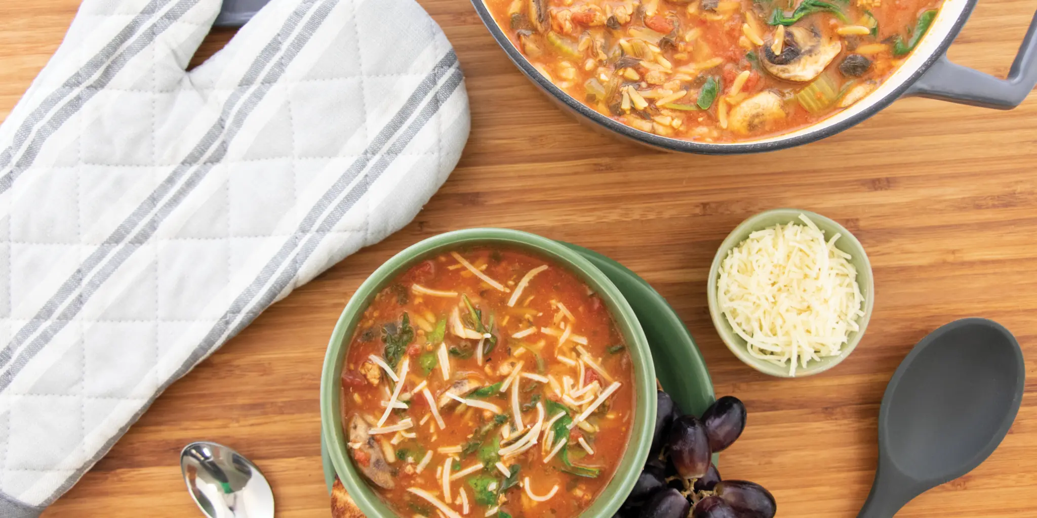 bowl of italian sausage orzo soup with larger pot next to it