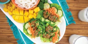 turkey lettuce wraps on a platter with cooked rice noodles and mango
