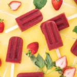 Popsicles are spread out over a yellow backdrop.