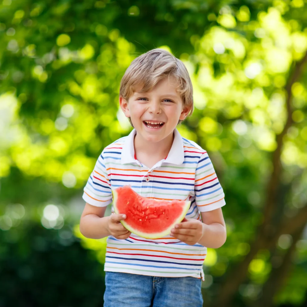 Child holding a watermelon.