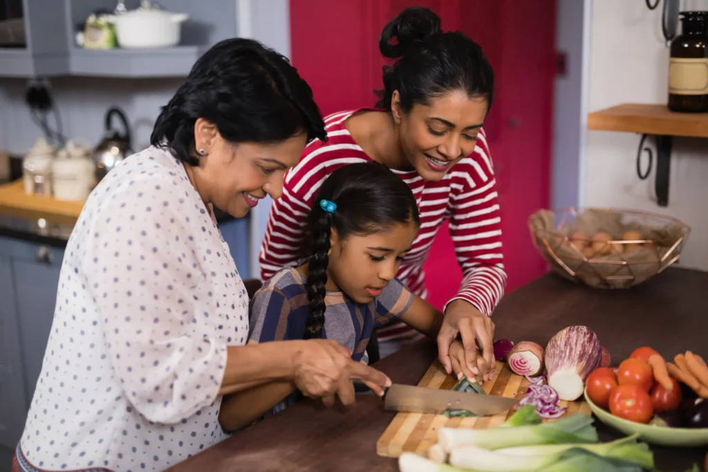 Mother and grandmother helping child cut veggies.