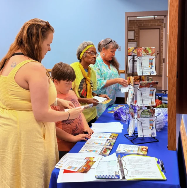Event attendees choose recipes and looking over materials that are tabled at event.