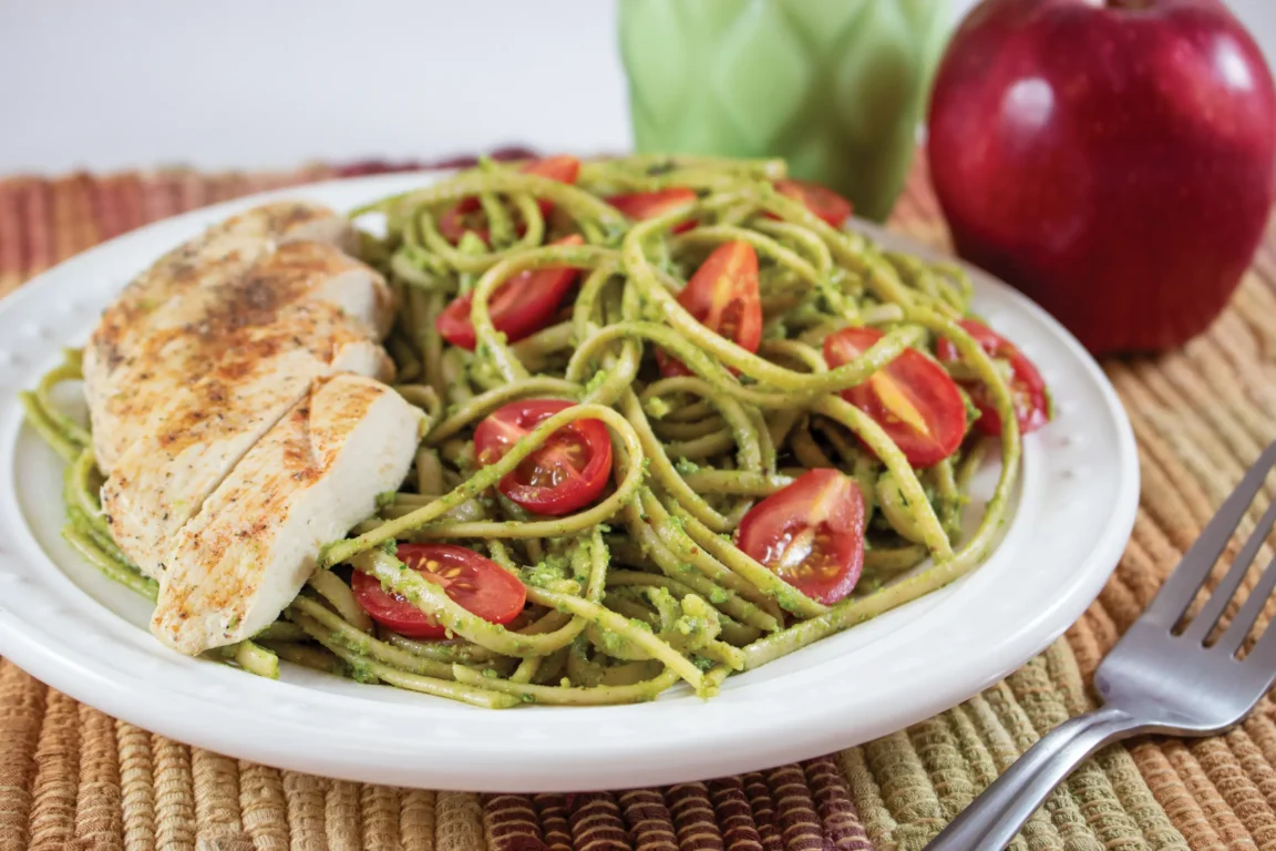 Pasta plated with chicken topped with garlic radish greens pesto